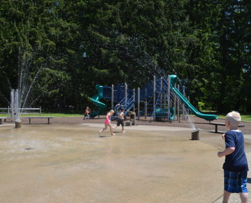 Children running through sprinklers at playground